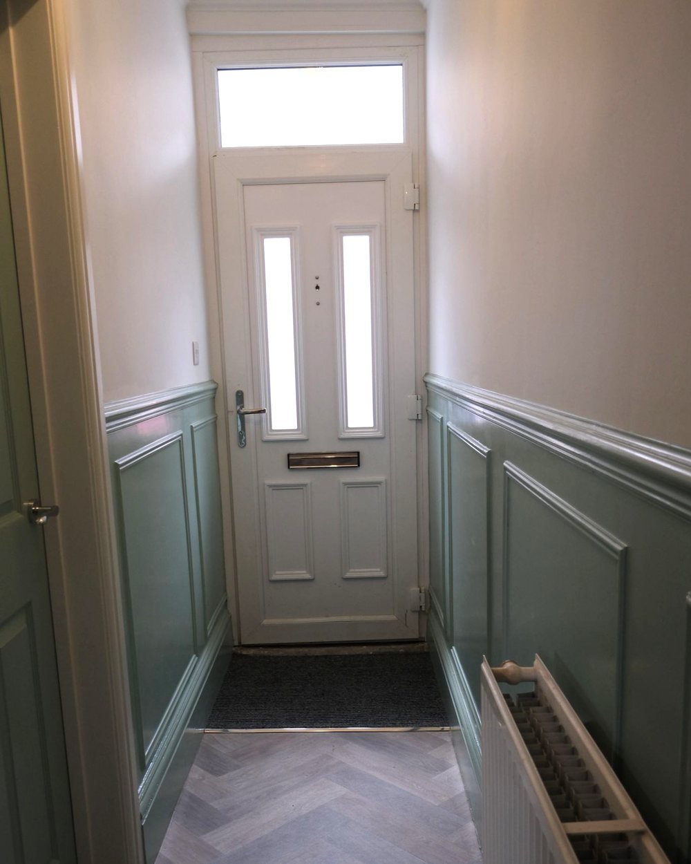 The same entrance hall after decorating, with sage green panelling and repainted woodwork