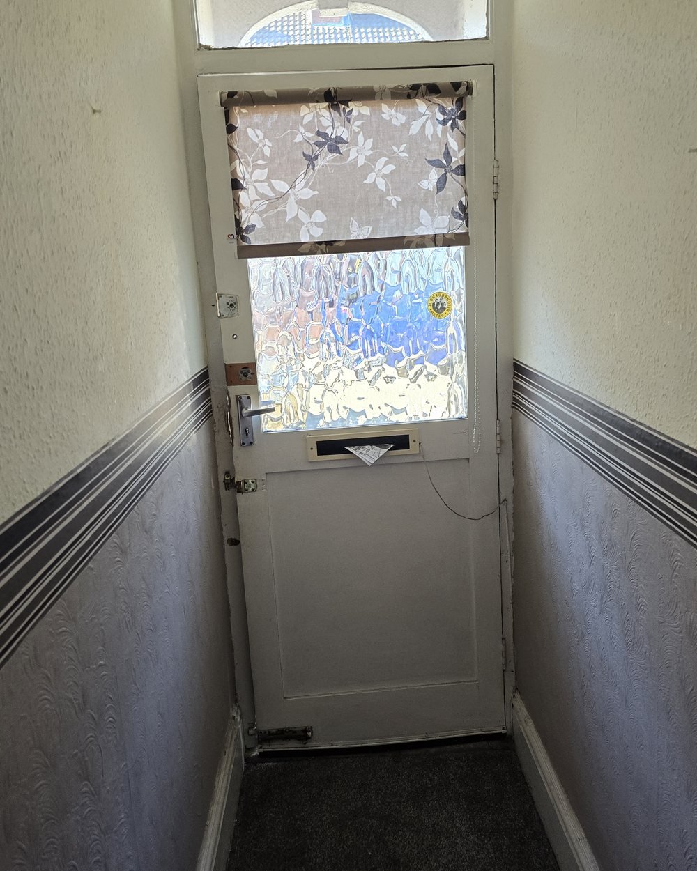 The entrance hall before decorating, with dated striped dado wallpaper and textured walls